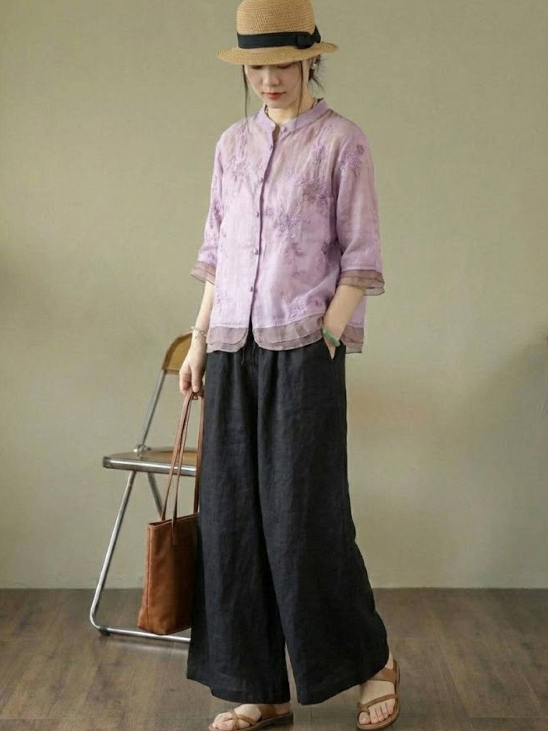 Woman wearing 100% cotton linen Tuscany two-piece set with embroidered top and wide-leg trousers in a bright room