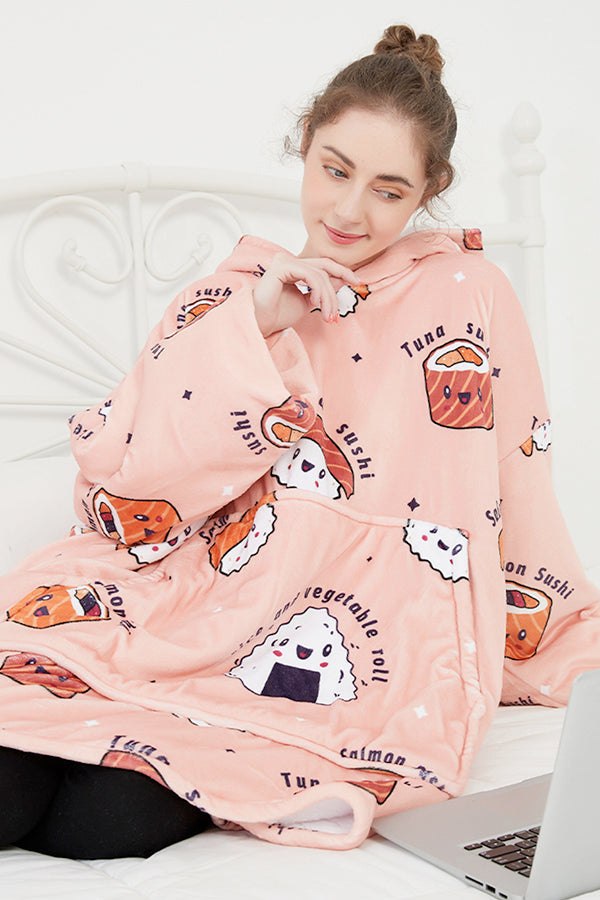 woman wearing snuggly oversized hooded fleece sweater with sushi print sitting on bed