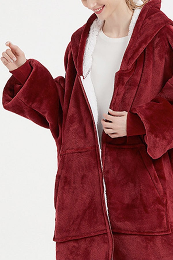 Woman wearing oversized ultra soft hooded blanket in burgundy with front pockets and zipper closure