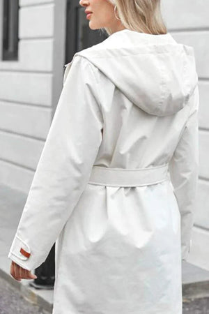 White water-resistant windbreaker trench jacket with hood and adjustable belt on woman outdoors
