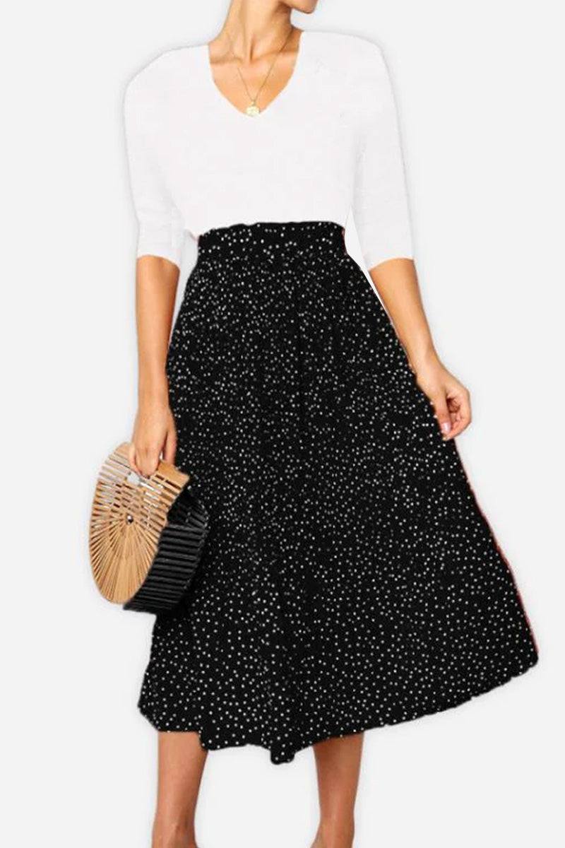 Woman wearing effortlessly chic polka dot pleated high-waist midi skirt with pockets and white shirt carrying a wooden handbag