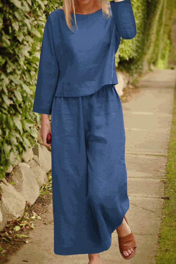 Woman wearing a loose solid color blue two-piece set with long sleeves and wide-leg pants walking outdoors