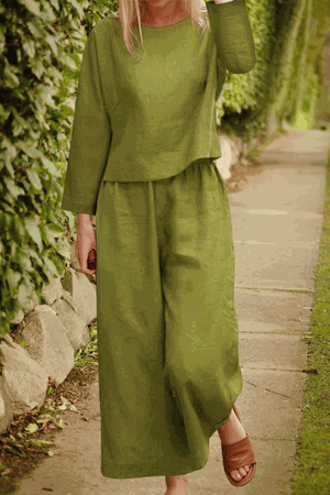 Woman wearing loose solid color olive green two-piece set with long sleeves and wide-leg pants outdoors