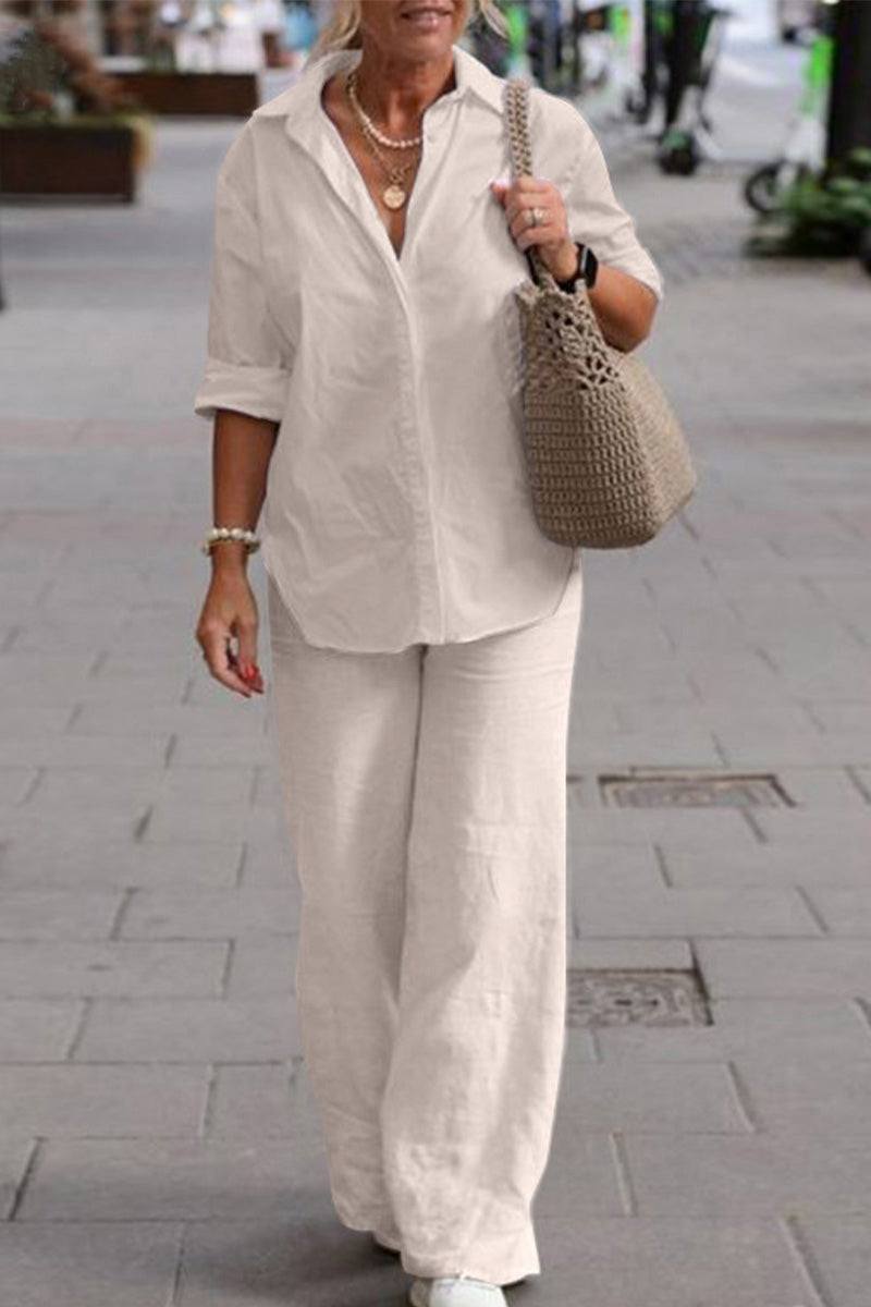 woman wearing relaxed shirt and trousers two-piece set in white walking outdoors carrying a woven bag