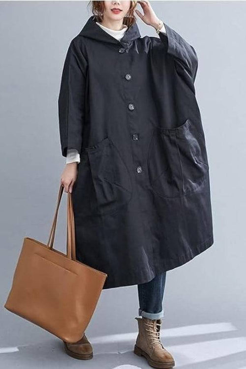 Oversized black water resistant windbreaker jacket with pockets and hood, styled with casual boots and brown tote bag