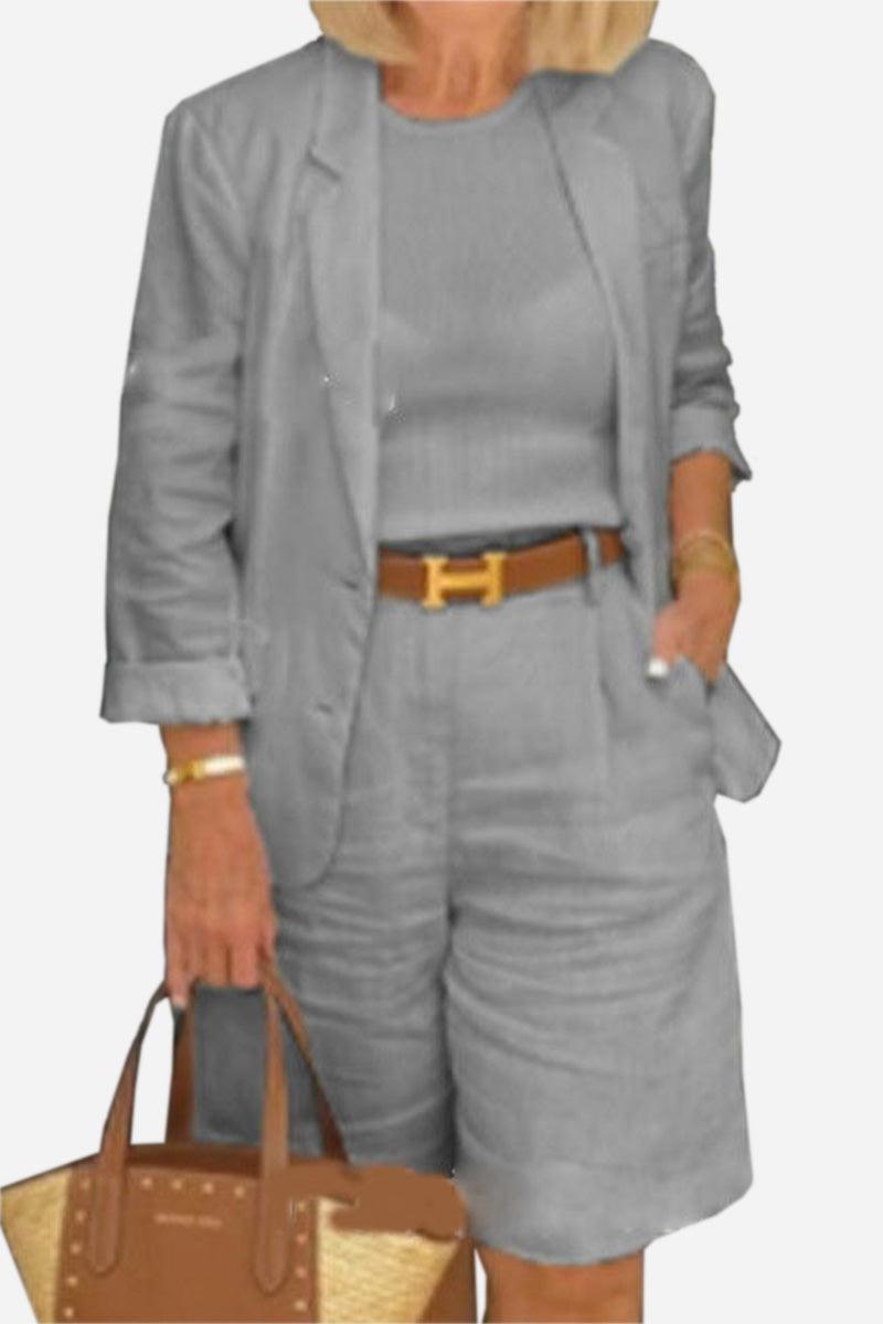 Woman wearing gray blazer and high-waisted shorts two-piece set with brown belt and handbag