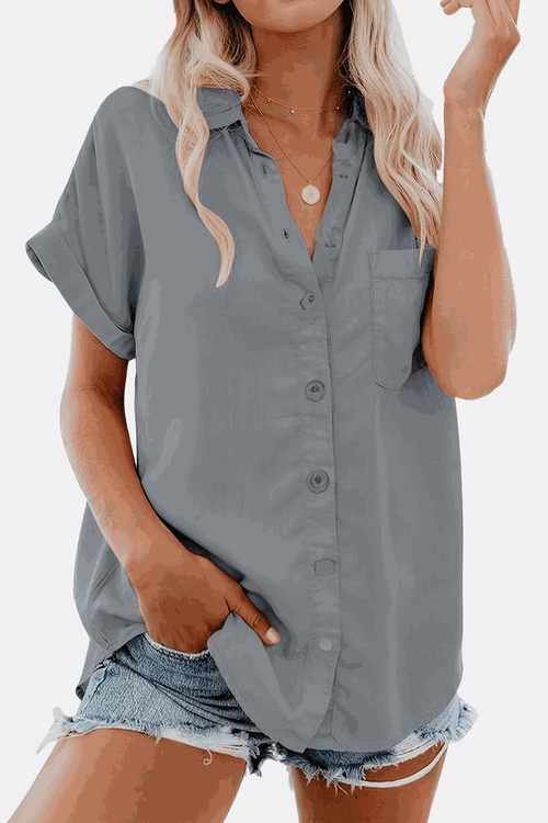Woman wearing gray V-neck collared button blouse with rolled sleeves and denim shorts