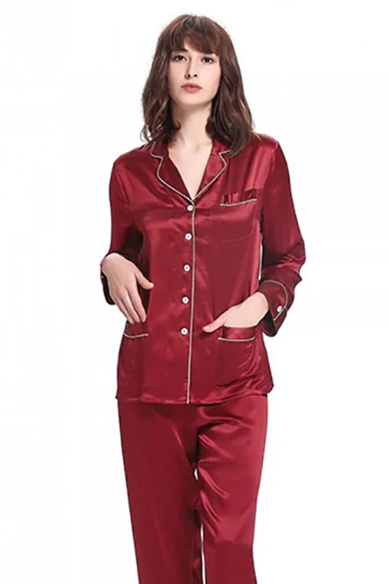 Woman wearing long sleeve silk pajamas in deep red mulberry color with button-up top and matching pants