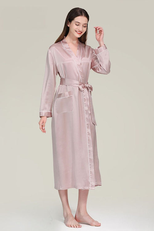 Woman wearing pink Mulberry silk nightgown with long sleeves and sash belt against neutral background