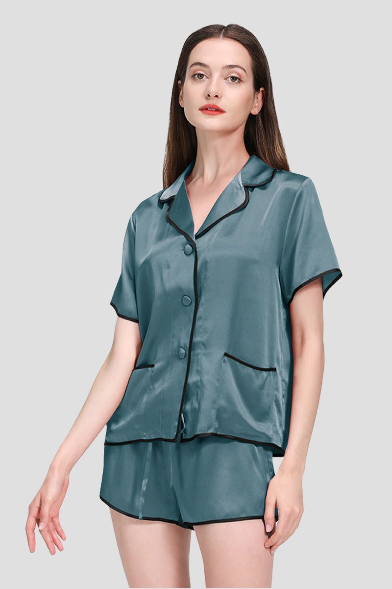 Woman wearing teal Mulberry Silk Hemd pajama set with black trimmed short sleeves and shorts