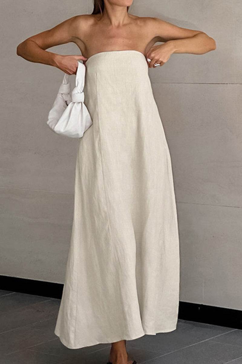 Woman wearing beige strapless A-line dress made of cotton linen blend fabric, holding a white handbag.