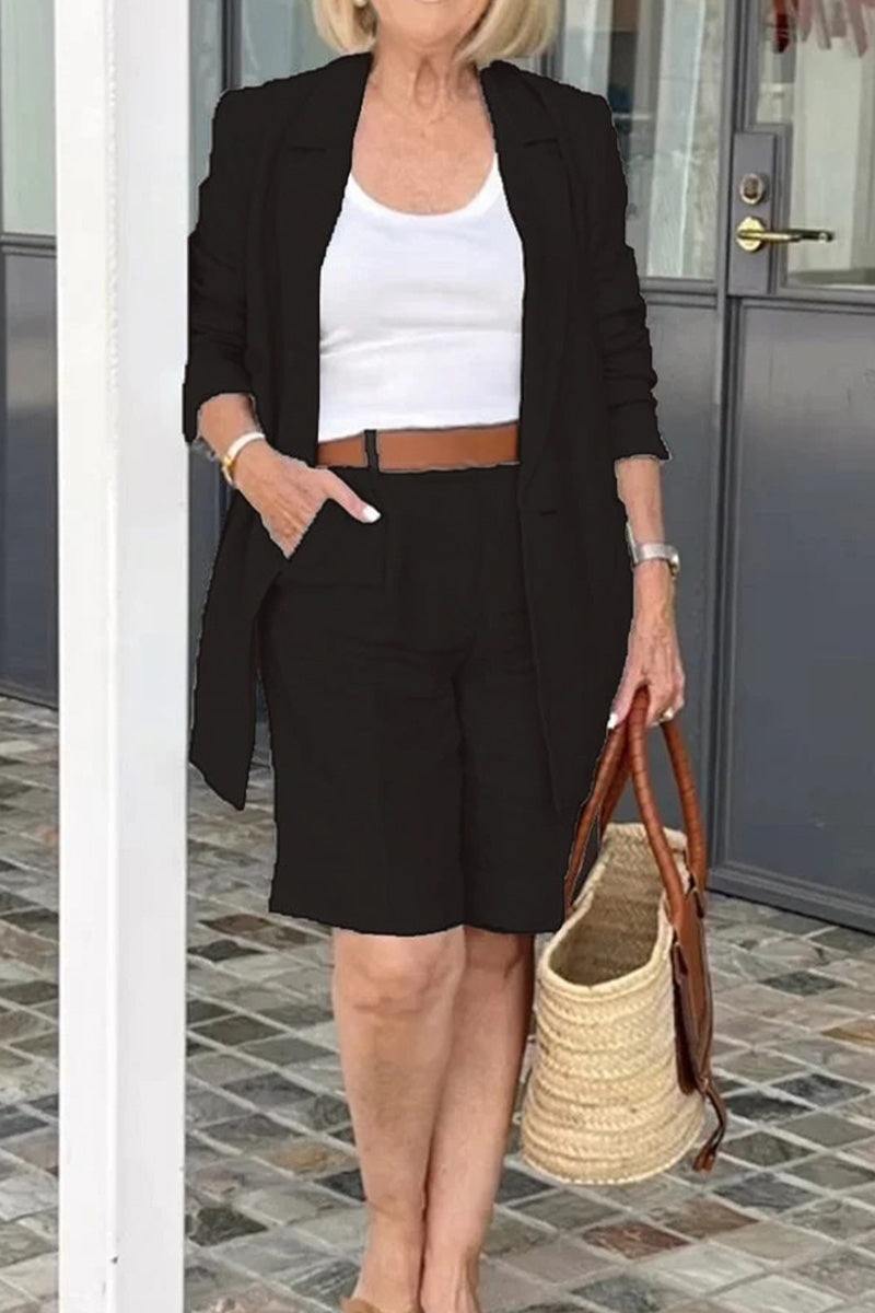 Stylish blazer and shorts two-piece set in black, worn with white top and brown belt, accessorized with woven tote bag.