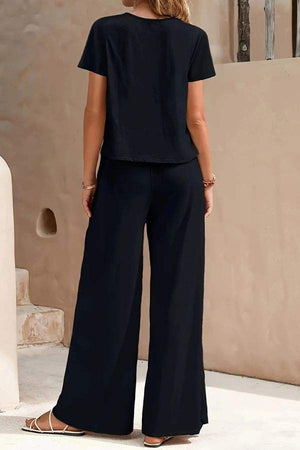 Woman wearing Riviera Relaxed Two Piece Set in black, featuring a loose short-sleeve top and wide-leg pants from the back.