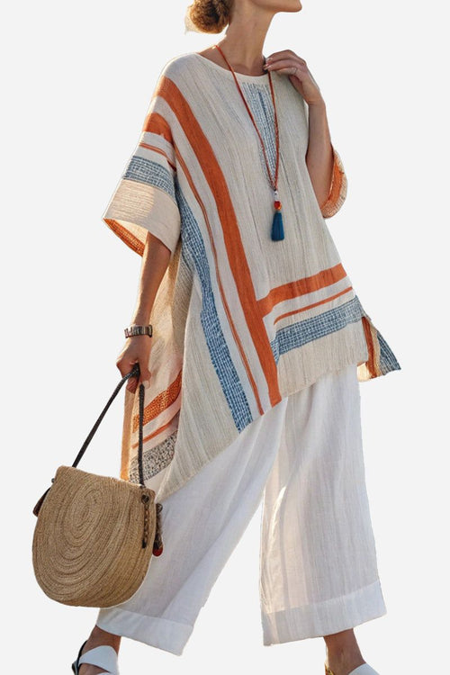 Woman wearing Coastal Comfort Linen two-piece set with wide-leg pants and striped linen tunic, holding round straw bag.