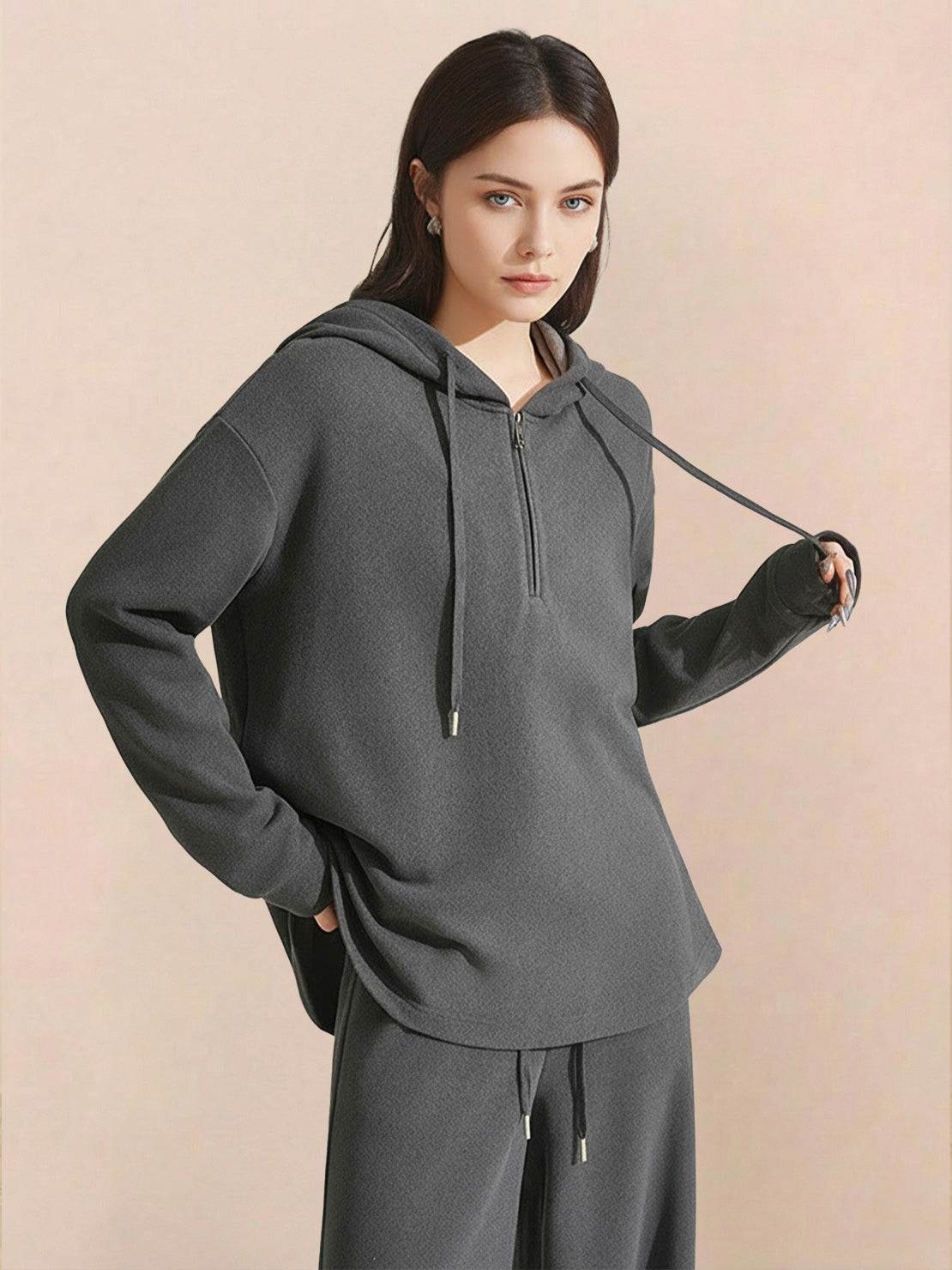 Woman wearing dark grey lyocell-blend hooded set with wide-leg pants and zip front top