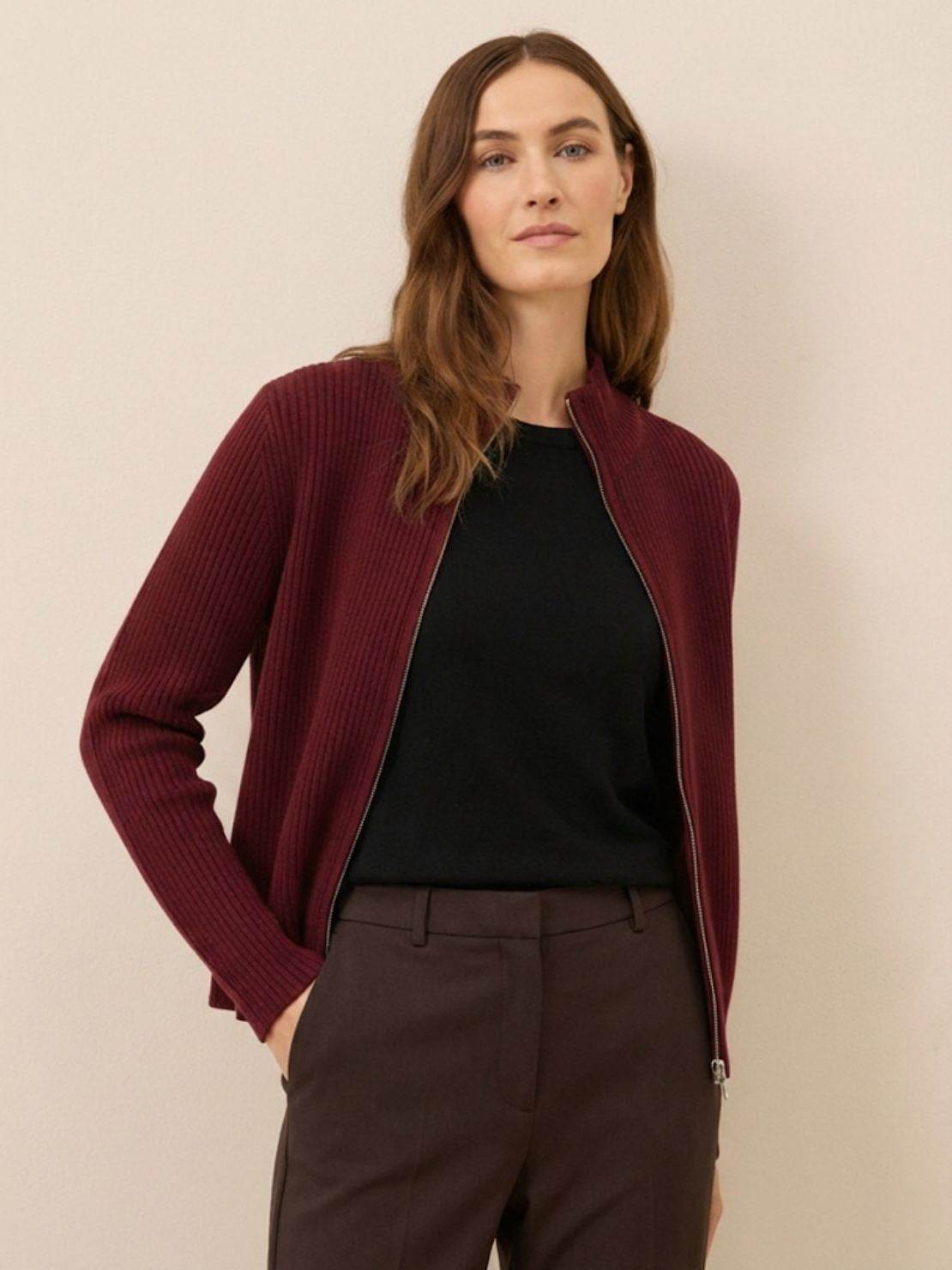 woman wearing a slim fit zip-up knit cardigan jacket with vertical ribbing and high neckline