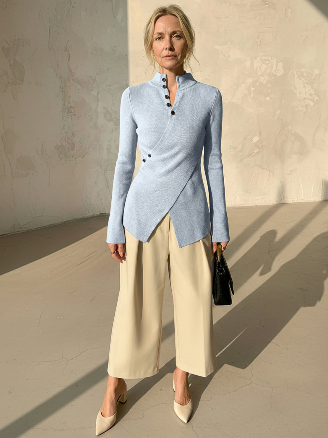 Woman wearing slim fit asymmetric wrap ribbed knit top with diagonal button closure and flared cuffs