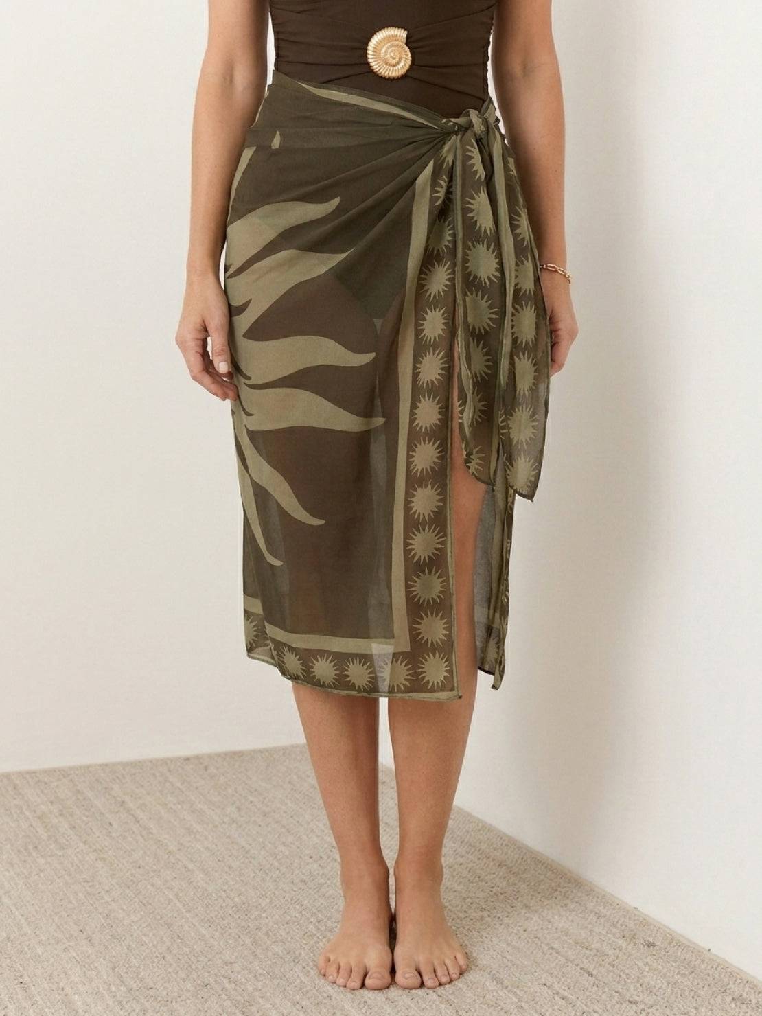 Deep-V swimsuit with ruched bust and waist, gold shell detail, wide straps, low back, high-cut leg, and sheer celestial print sarong wrap