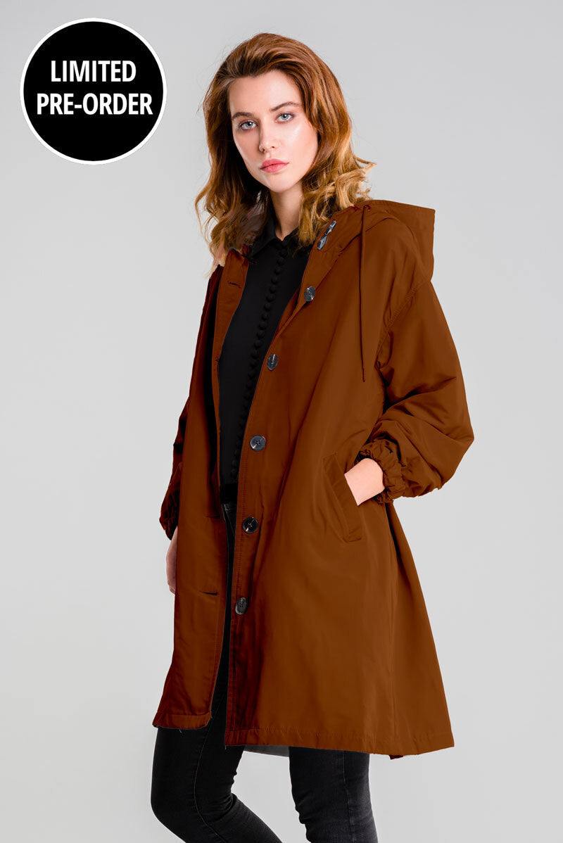 Water Resistant Oversized Windbreaker in brown with hood and button closure on female model against gray background