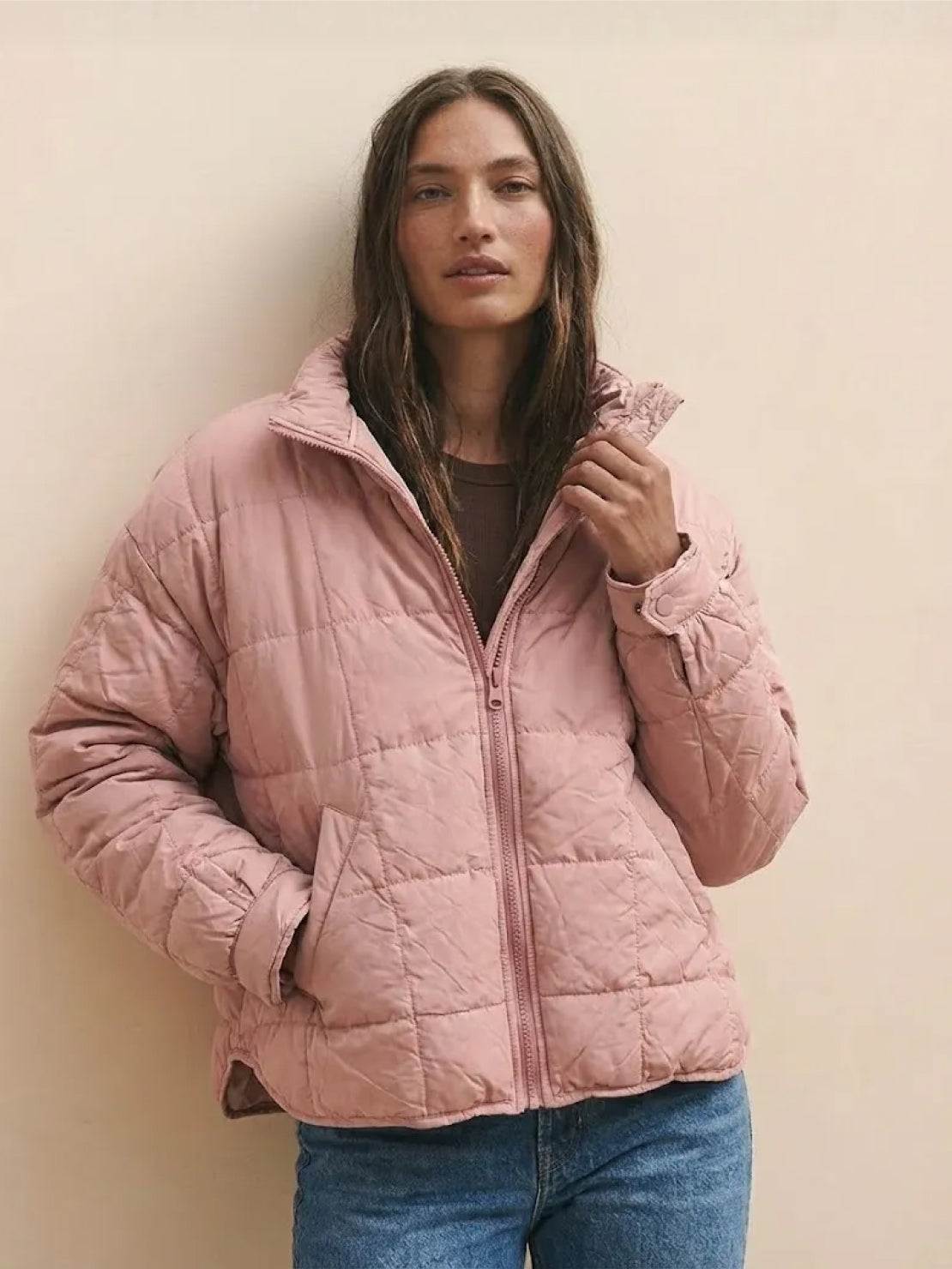 woman wearing pink lightweight puffer travel jacket with front zipper and pockets