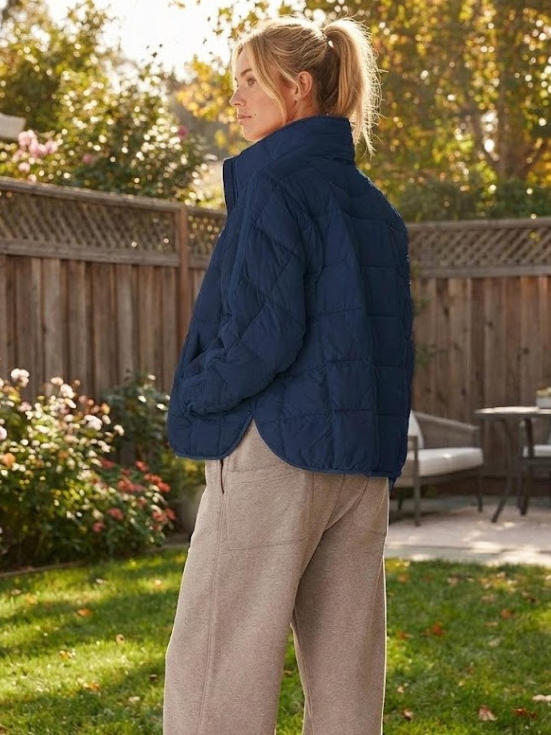 Woman wearing navy lightweight puffer travel jacket outdoors on a sunny day