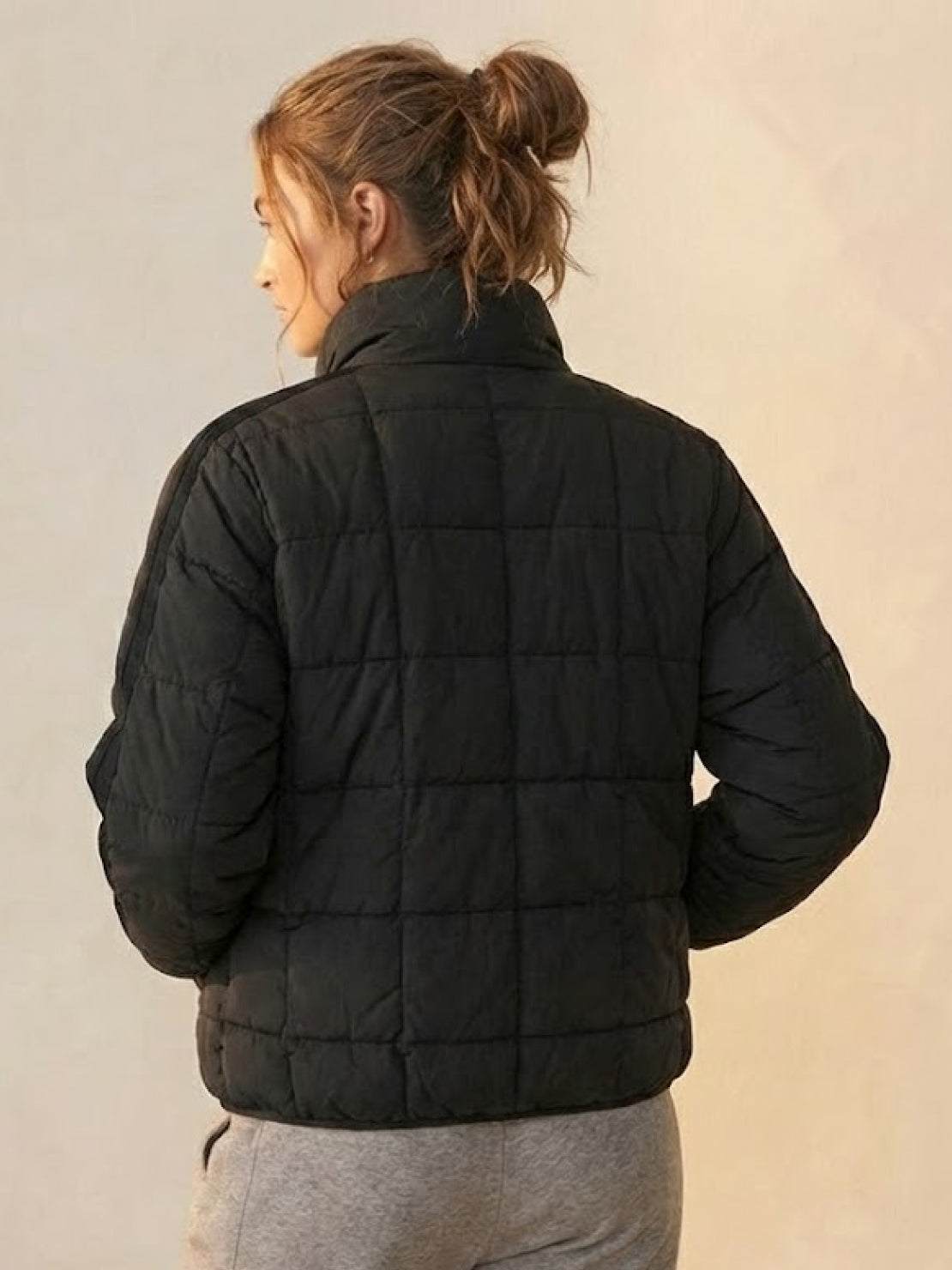 Woman wearing black lightweight puffer travel jacket from the back