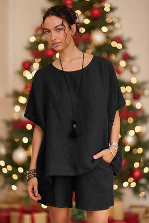 Woman wearing black comfy linen-like shirt and shorts two-piece set in front of Christmas tree background