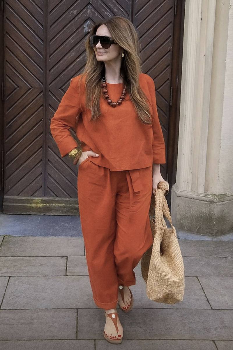 Woman wearing relaxed cotton-linen monochrome capsule outfit in burnt orange with wide-leg pants and longline top.