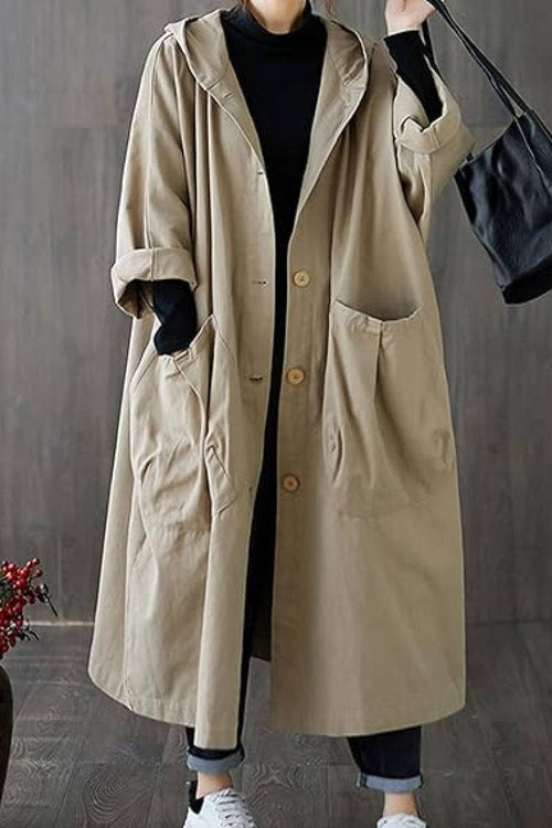 Oversized beige water resistant windbreaker jacket with hood and large pockets worn over black outfit