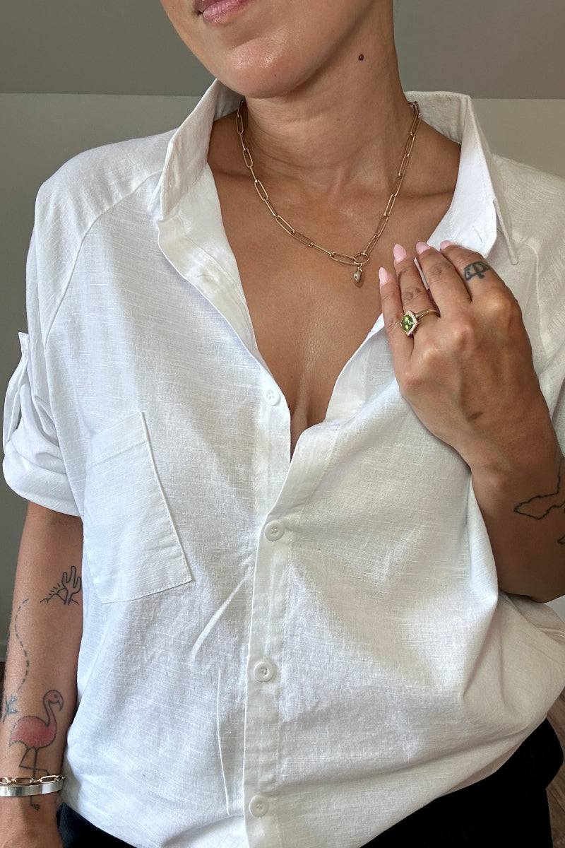 Woman wearing a relaxed fit oversized linen shirt in white with rolled-up sleeves and button front closure