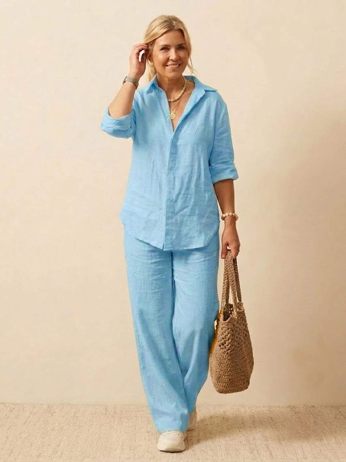 Woman wearing oversized 100% cotton light blue shirt and wide-leg pants co-ord set with a woven bag.