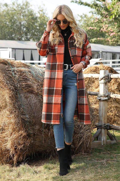 Woman wearing oversized medium-length plaid overshirt in shades of orange and brown, paired with jeans and black boots outdoors near hay bales