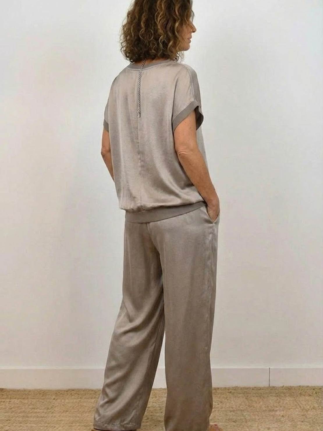 Woman wearing Silken Escape Satin Two-Piece Set with flowy satin top and wide-leg pants in elegant pose