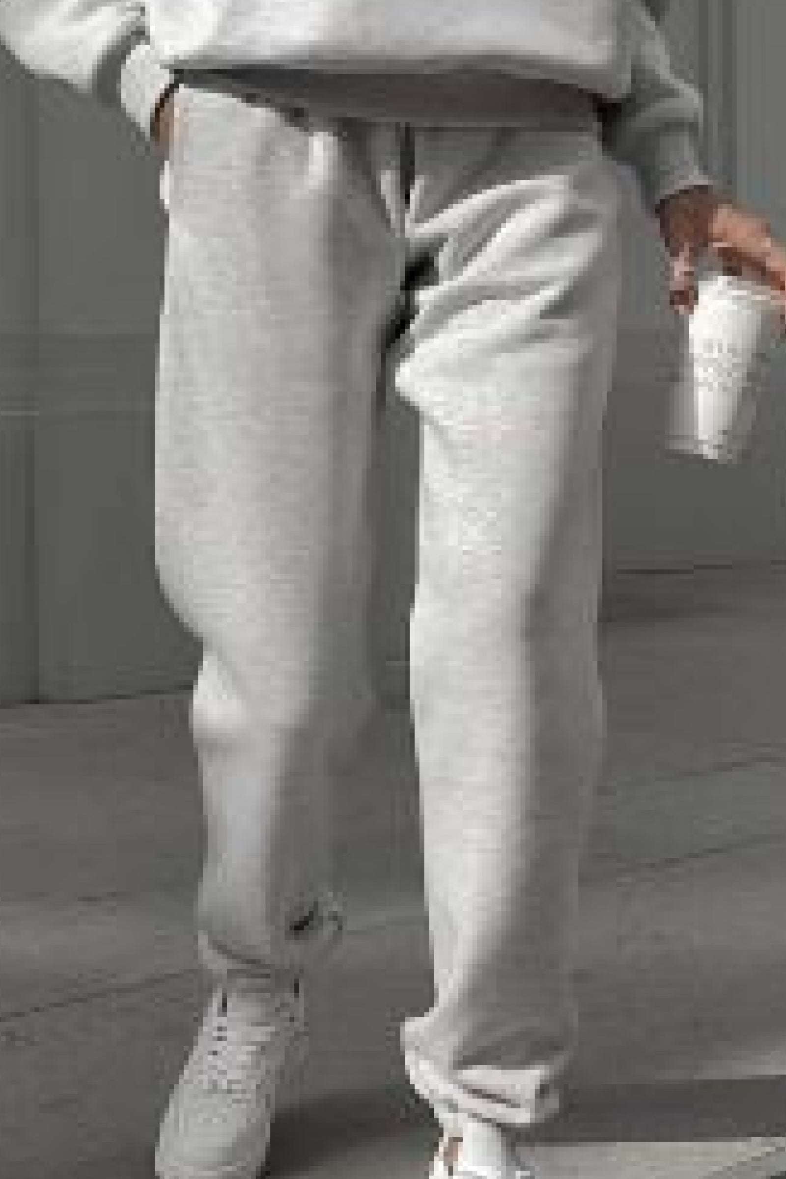 Close-up of light gray cotton blend tracksuit pants worn with white sneakers, casual loungewear style.