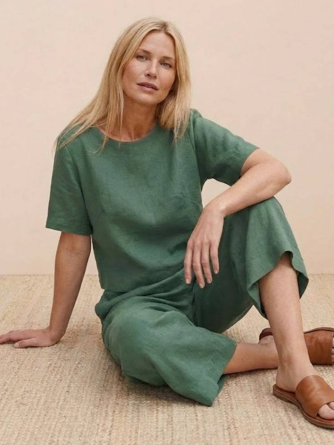 Woman wearing green loose fit co-ord set with short sleeves and wide-leg pants sitting on woven rug.