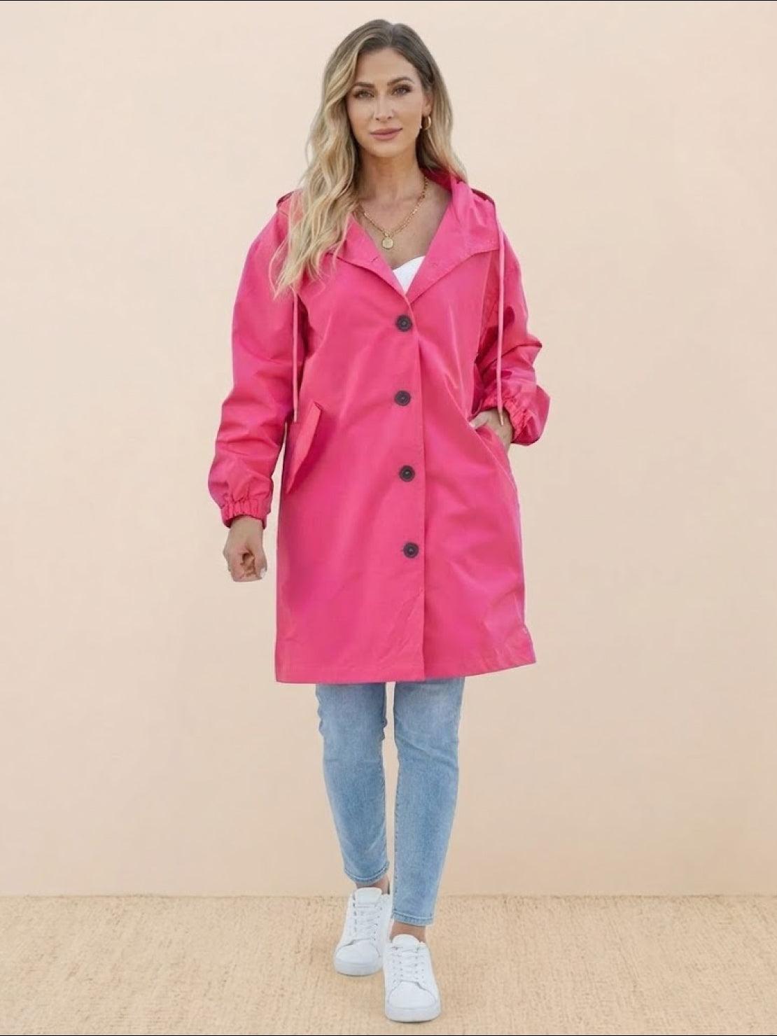 Woman wearing trendy oversized pink Rain Couture Windbreaker jacket with buttons and pockets, paired with jeans and white sneakers