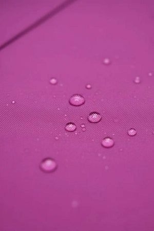 Close-up of water-repellent fabric with water droplets on purple surface for raincoat