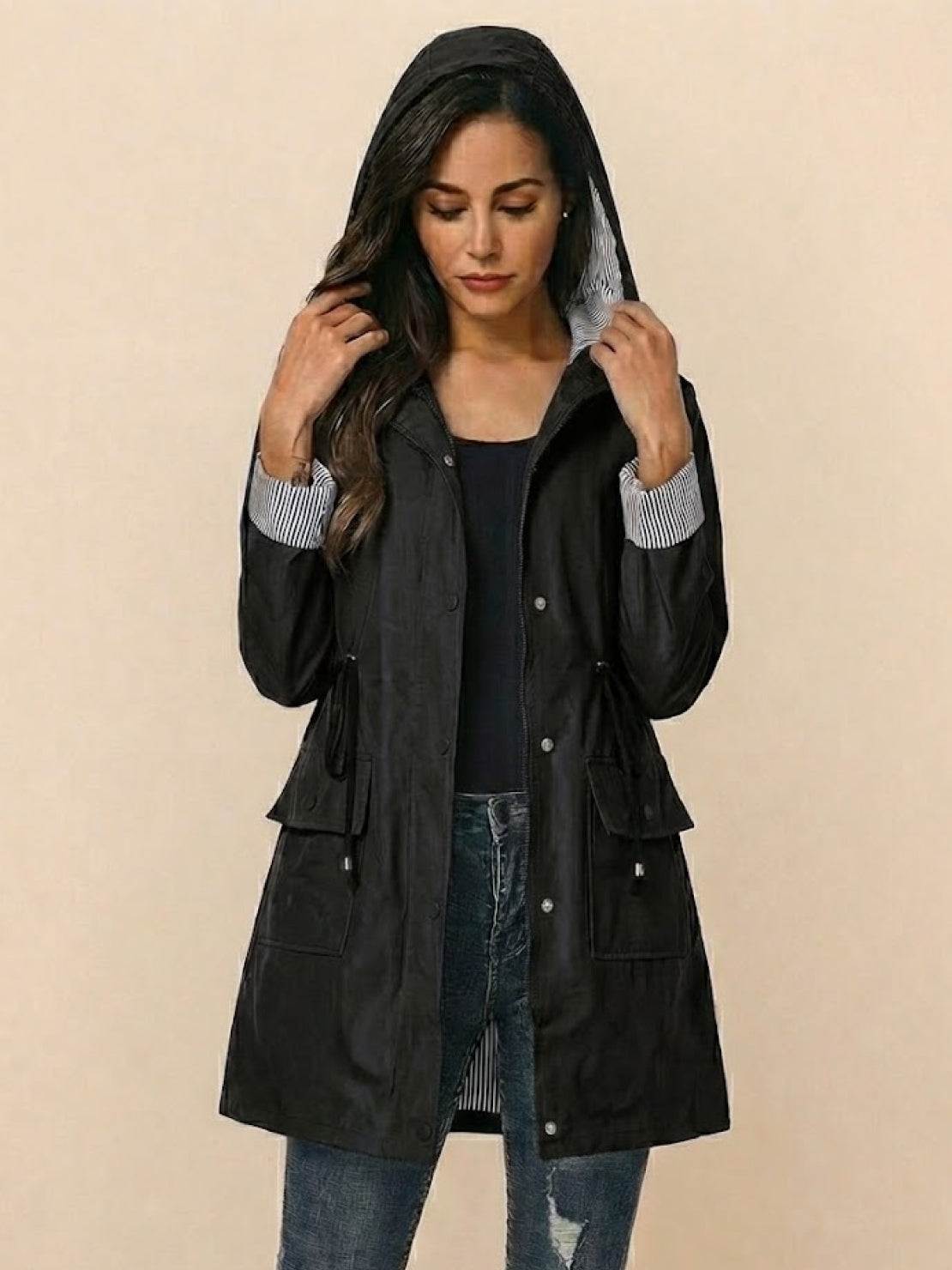 Woman wearing black water resistant hooded striped windbreaker jacket with pockets and oversized fit