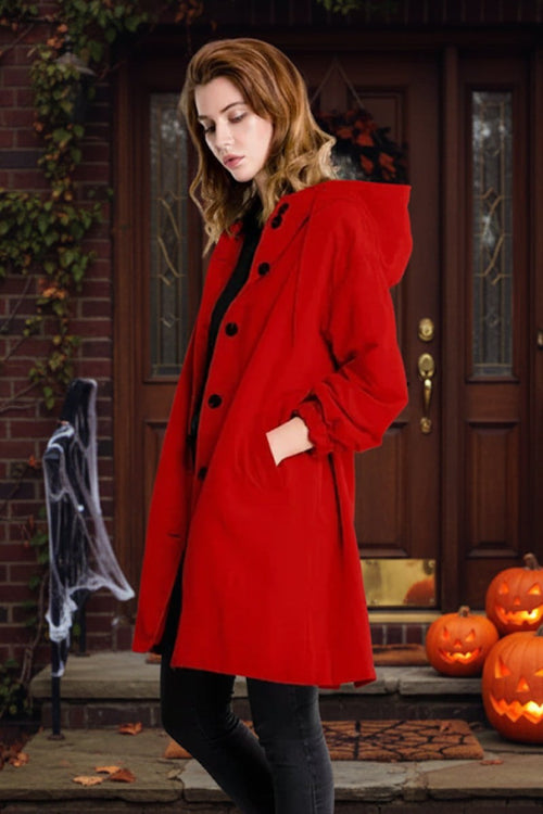 Woman wearing a red water-resistant oversized hooded windbreaker rain jacket standing by a Halloween-decorated front door with pumpkins.