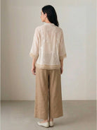 Light beige 100% cotton linen Tuscany two-piece set with sheer embroidered top and wide-leg trousers on white background