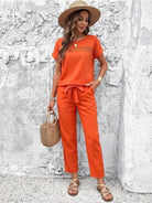 woman wearing orange 100 cotton total comfort two-piece travel set with hat and woven bag against textured white wall