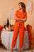 Woman wearing orange 100% cotton Total Comfort Two-Piece Set from Halloween Collection in festive indoor setting with seasonal decorations