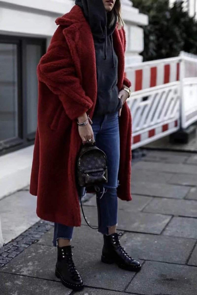 Woman wearing a red glamour teddy coat with loose fit, paired with jeans and black boots on city street