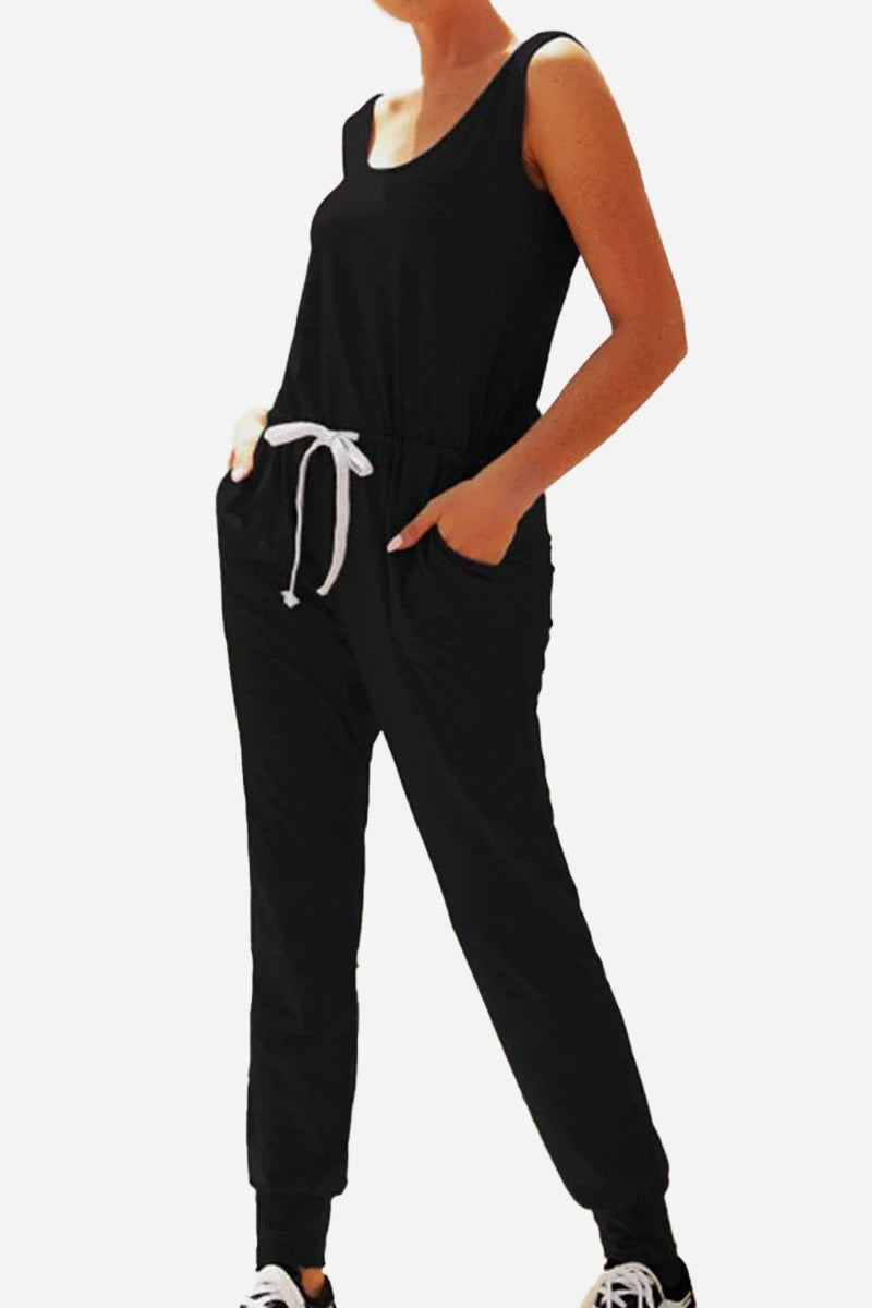 Woman wearing black comfy sleeveless vest pocket jumpsuit with elastic waistband and drawstring