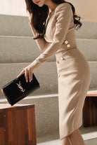 Beige stylish button pencil dress with v-neck and asymmetrical waist, worn with black clutch bag
