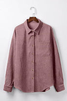Sleek suede oversized button-down shirt in mauve with front pocket and button closure hanging on wooden hanger
