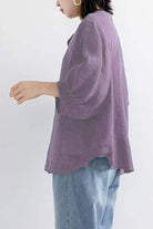Relaxed loose breathable linen blouse in purple worn with jeans, side view