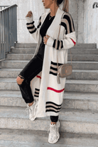 Cozy striped long knitted cardigan with oversized fit and soft fabric on model wearing black outfit