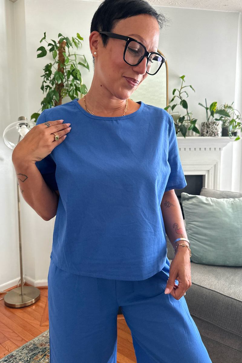 woman wearing blue loose fit co-ord set with short sleeves and wide-leg pants in a cozy living room setting