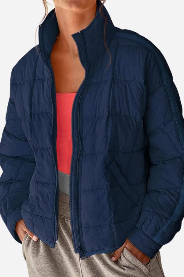 woman wearing navy lightweight puffer travel jacket with zipper and hands in pockets